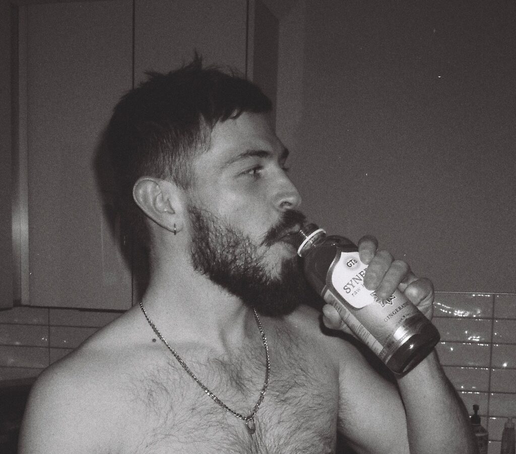 Aidan drinks kombucha in the kitchen.